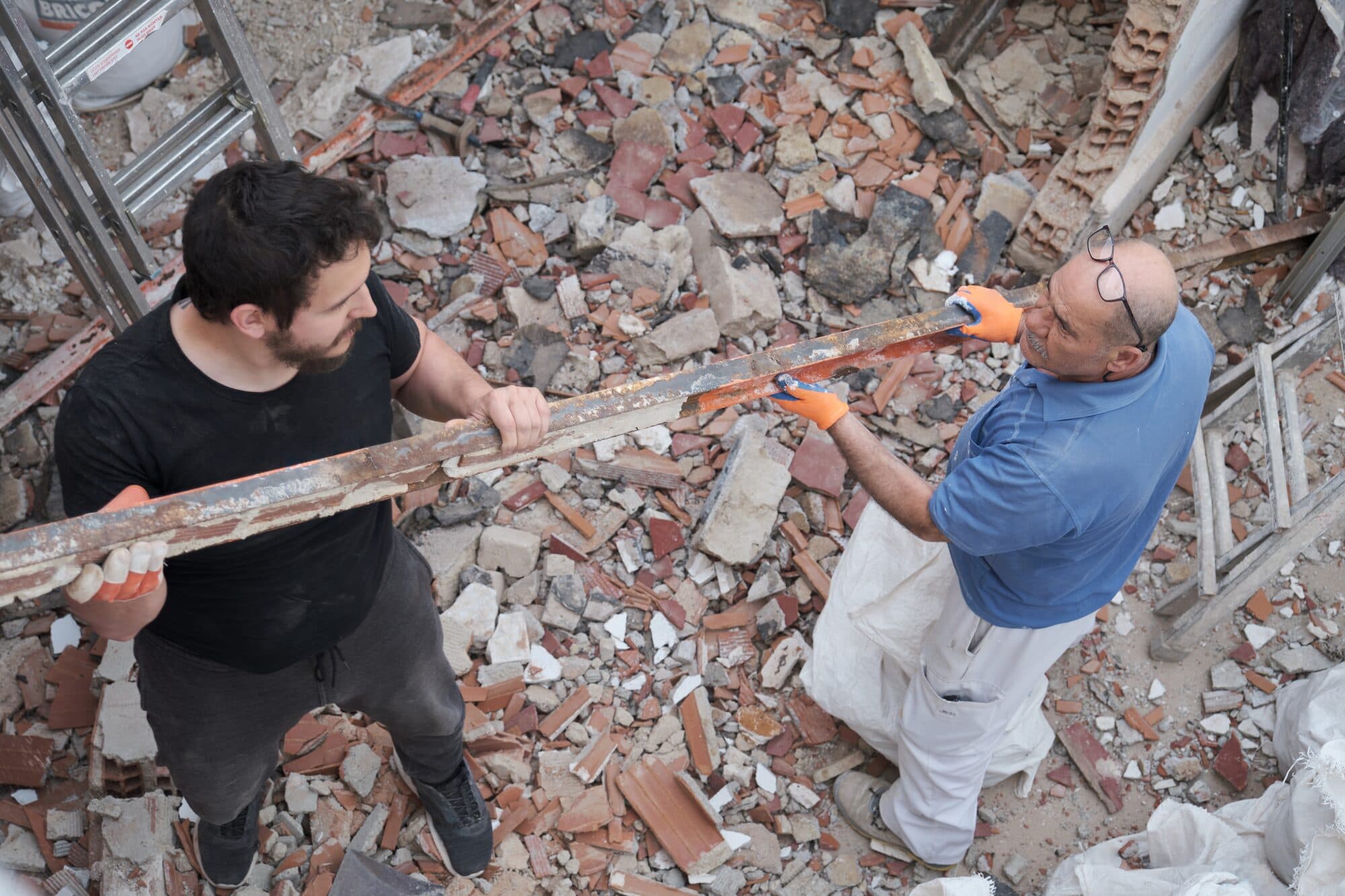 To medarbejdere rydder murbrokker ved en nedrivning
